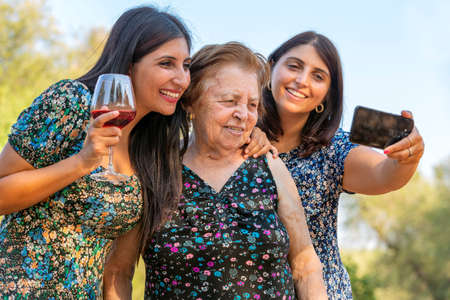 Grandmother and grandchildren taking a selfie at a party while drinking wine. New normal lifestyle concept with happy people having fun together outdoorsの写真素材