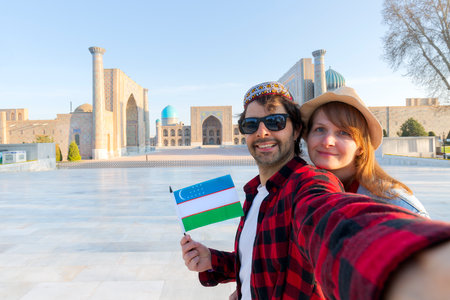 happy couple of tourists taking a selfie with Registan as background in the city of Samarkand, Uzbekistan, Central Asiaの写真素材