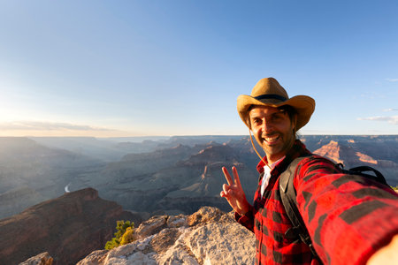 Grand Canyon National Park in Arizona, United States. Tourist taking a selfie photo during a hike. Young adult male traveler.の写真素材