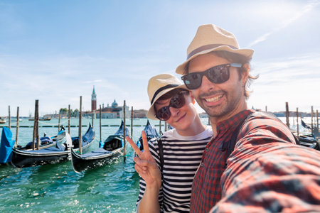 young couple taking a selfie and having fun while visiting Venice. Tourists traveling to Italy and visiting the most important monuments of Venice. Lifestyle conceptsの写真素材