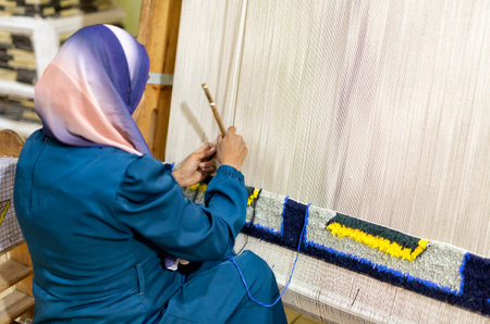 Weaving and production of handmade carpets up close. women's hands weave a carpet. A woman's hand sewing a tapestry.の写真素材