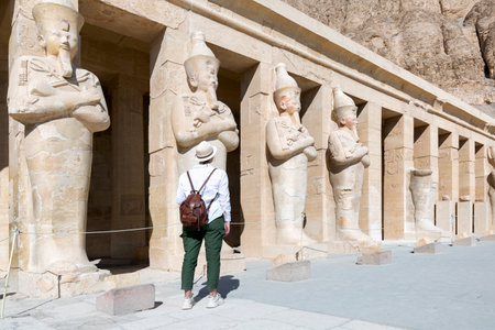 Happy woman traveler explores the ruins of the ancient Egyptian Hatshepsut temple in the heritage city of Luxor. Wonders of the World and tourist experienceの写真素材