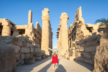A beautiful young girl standing examining historical artifacts - Ancient Temple of Karnak in Luxor - Ruined Thebes Egyptの写真素材