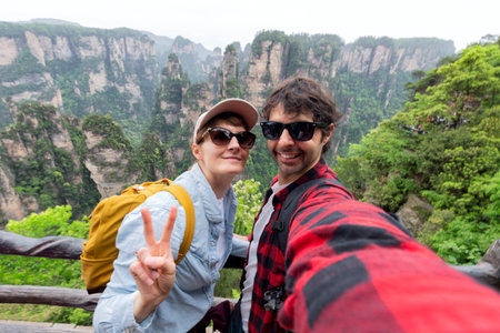 A couple traveler is taking selfie with the background view of "Zhangjiajie" limestone mountain cliff. Here is amazing natural landmark of China.の写真素材