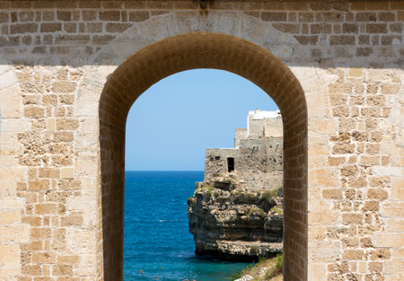 Polignano a Mare, Italy. Beach between the rocks. View of the sea and the beach. Old buildings on a cliff by the sea. Italian architecture. Photos for backgrounds, wallpapers, postcards.の写真素材