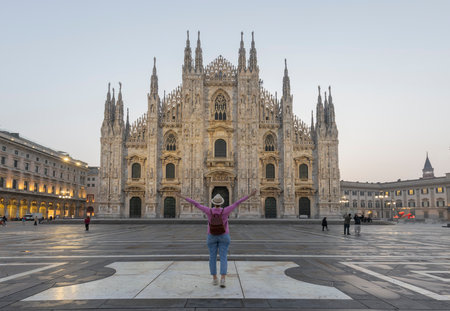 Rear view of traveler girl holds hat in Milan Cathedral Square, Italy.の写真素材