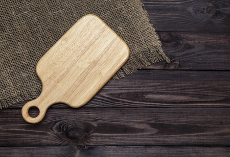 Empty cutting board on a dark wooden table. View from aboveの写真素材