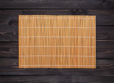orange bamboo napkin on a dark wooden table, top viewの写真素材
