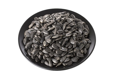 Black sunflower seeds in dish, isolated on white background with clipping pathの写真素材