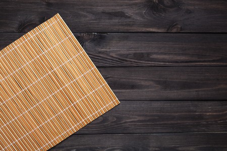 orange bamboo napkin on a dark wooden table, top viewの写真素材