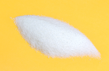 Close-up of pile of sugar isolated on a yellow backgroundの写真素材