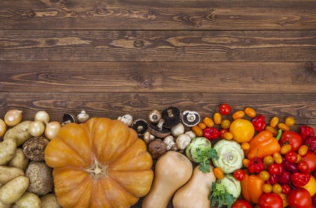 Autumn harvest on wooden table background. Pumpkin, zucchini, potatoes, onions and other vegetablesの写真素材