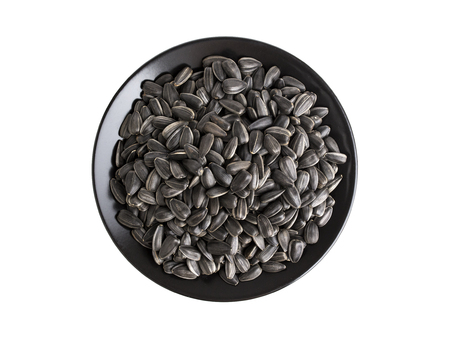 Black sunflower seeds in dish, isolated on white background with clipping pathの写真素材