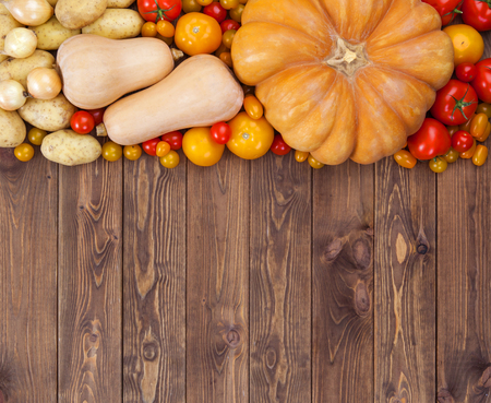 Autumn harvest on wooden table background. Pumpkin, zucchini, potatoes, onions and other vegetablesの写真素材