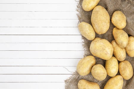 Raw potatoes isolated on a white wooden background, top viewの写真素材