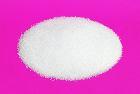 Close-up of pile of sugar isolated on yellow backgroundの写真素材