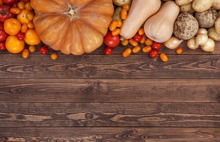 Autumn harvest on wooden table background. Pumpkin, zucchini, potatoes, onions and other vegetablesの写真素材