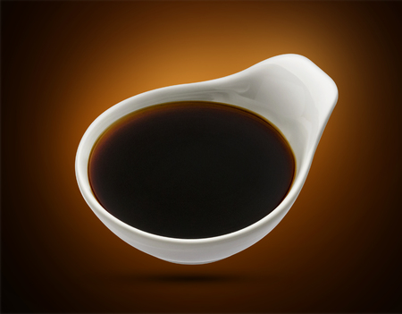 Bowl with soy sauce isolated on black backgroundの写真素材