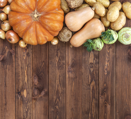 Autumn harvest on wooden table background. Pumpkin, zucchini, potatoes, onions and other vegetablesの写真素材