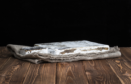 Dark background for product montage. Old wooden cutting board with tablecloth and black backgroundの写真素材