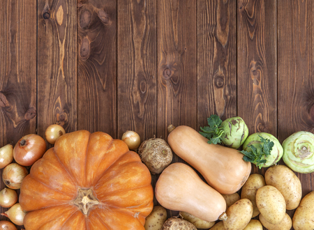 Autumn harvest on wooden table background. Pumpkin, zucchini, potatoes, onions and other vegetablesの写真素材