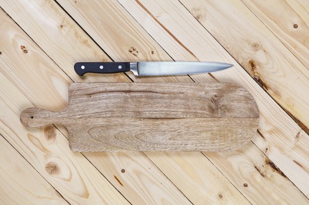 Cutting board with a knife on a wooden table. top viewの写真素材