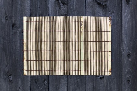 Bamboo mat on dark wooden table, top viewの写真素材