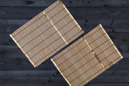 Bamboo mat on dark wooden table, top viewの写真素材