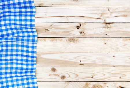 Blue checkered tablecloth on a light wooden table, top viewの写真素材