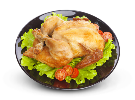 Roasted chicken on plate isolated on white background with lettuce and tomatoesの写真素材