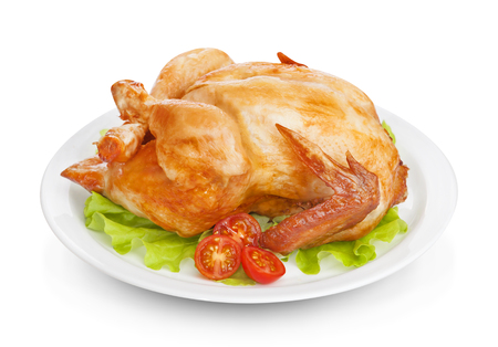 Roasted chicken on plate isolated on white background with lettuce and tomatoesの写真素材