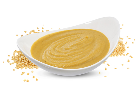 Mustard sauce in bowl and mustard seeds isolated on white backgroundの写真素材