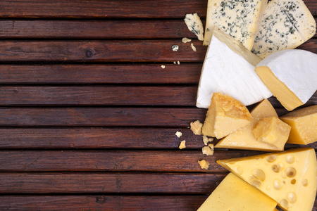 Various cheeses on wooden table with empty space.の写真素材