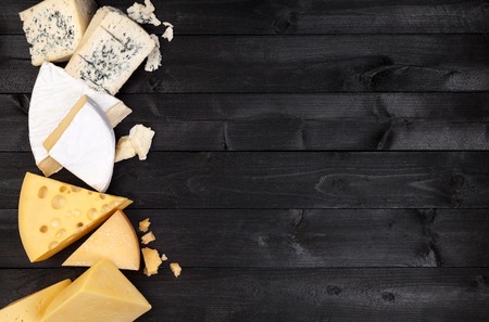 Different types of cheese on black wooden table. Top viewの写真素材