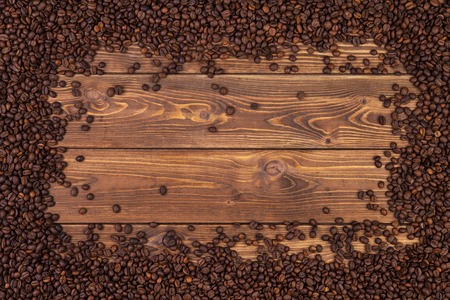 Coffee beans background. Frame of coffee beans on brown wooden table. Top view with copy spaceの写真素材