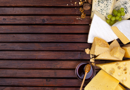 Various cheeses on wooden table with empty space.の写真素材