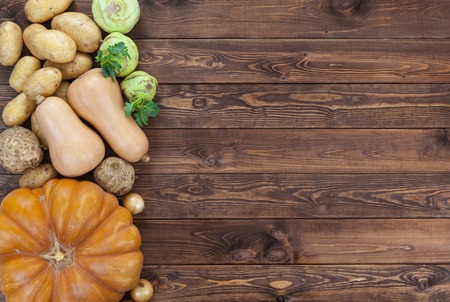 Vegetables on wooden background. Pumpkin, zucchini, potatoes, onions and other vegetables, top view, copy spaceの写真素材