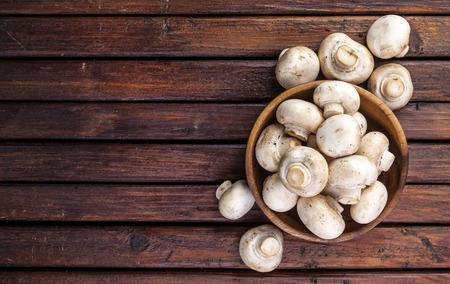 Top view of mushrooms champignon on wooden table. Copy space.の写真素材