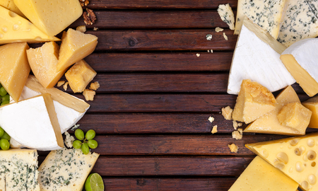 Various types of cheese on wooden table background. Cheddar, parmesan, emmental, blu cheese. Top view, copy space.の写真素材