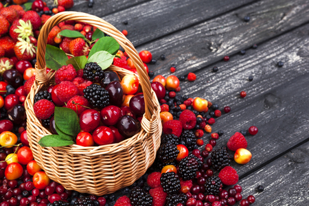 Fresh forest berries in basket on rustic wooden background. Copy spaceの写真素材
