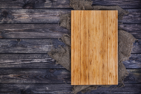 Cutting board on dark wood background, top viewの写真素材