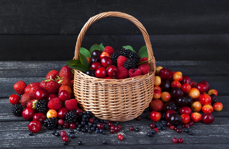 Fresh forest berries in basket on rustic wooden background. Copy spaceの写真素材