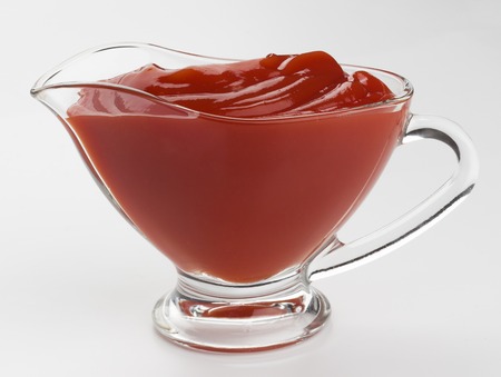 Glass bowl of ketchup isolated on white backgroundの写真素材