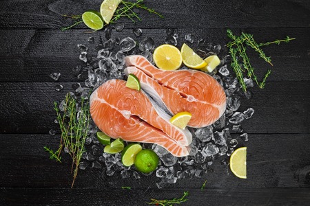 Salmon steaks on black wooden background top viewの写真素材