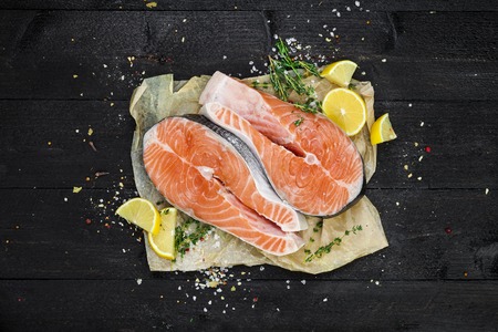 Salmon steaks on black wooden table top viewの写真素材