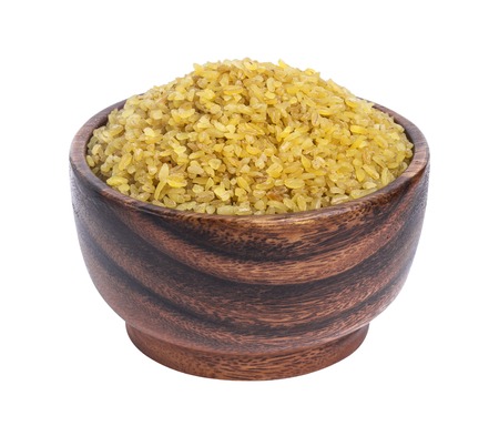 Dry bulgur wheat in wooden bowl isolated on white backgroundの写真素材
