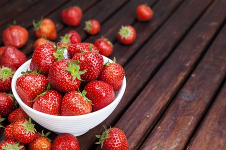 Strawberry in bowl on wooden table. Copy spaceの写真素材