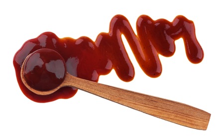 Splash of ketchup sauce with wooden spoon isolated on white background. Top viewの写真素材