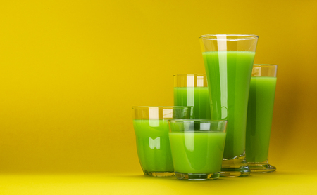 Organic green smoothie, apple juice on isolated on yellow background with copy space, fresh celery cocktailの写真素材