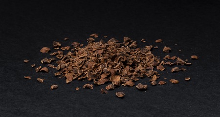 Grated chocolate. Heap of ground chocolate isolated on black background, closeup